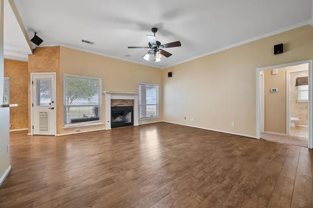 an empty room with wooden floor fireplace and windows