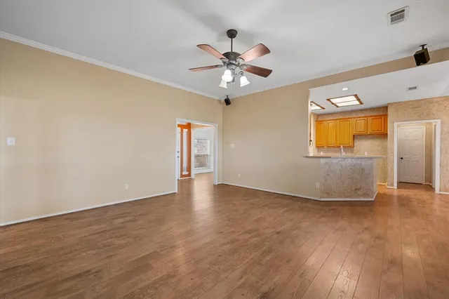 an empty room with wooden floor fan and windows