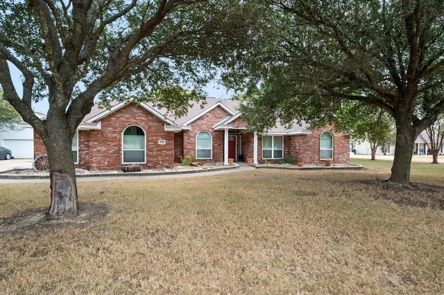 a front view of a house with yard and tree