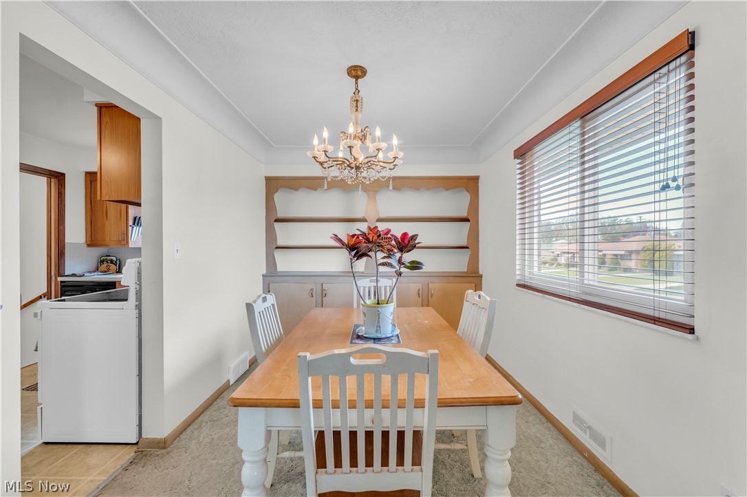3023 Norris Avenue Cleveland, OH 44134 - Photo 9 of 41 Bright dining area featuring a chandelier, a built-in wooden hutch, and a large window with horizontal blinds