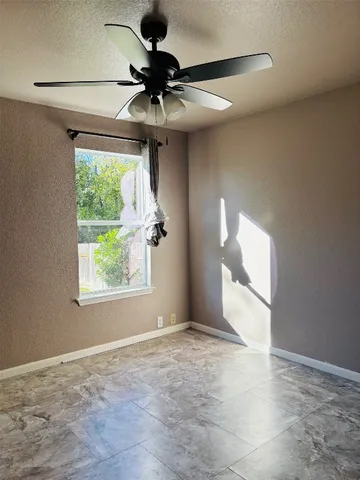a view of an empty room and window and chandelier fan