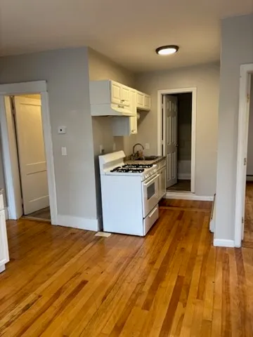 a view of an empty room with wooden floor and closet