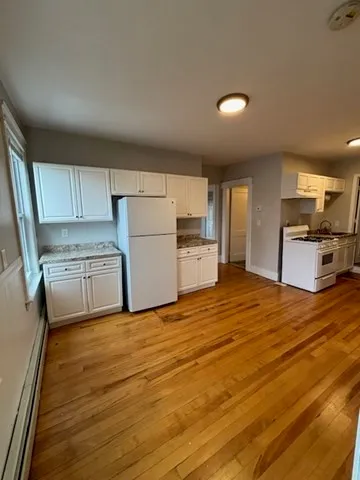 a kitchen with granite countertop a refrigerator stove and white cabinets
