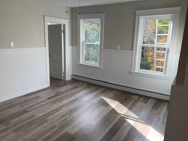 an empty room with wooden floor chandelier fan and windows