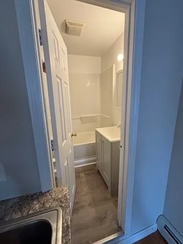 a bathroom with a granite countertop sink a mirror and a bathtub
