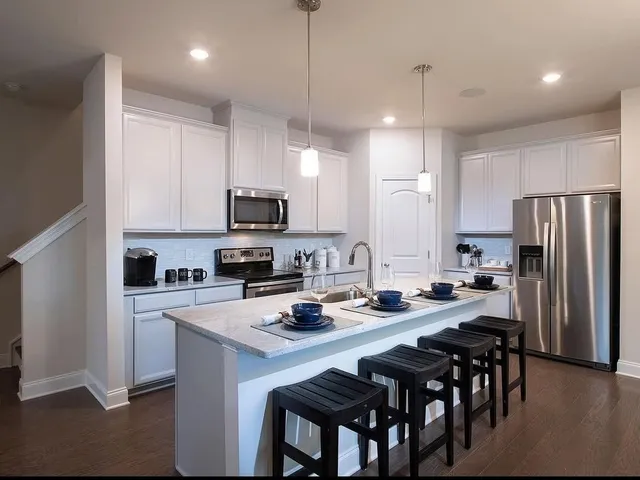 a kitchen with refrigerator a stove a sink and chairs