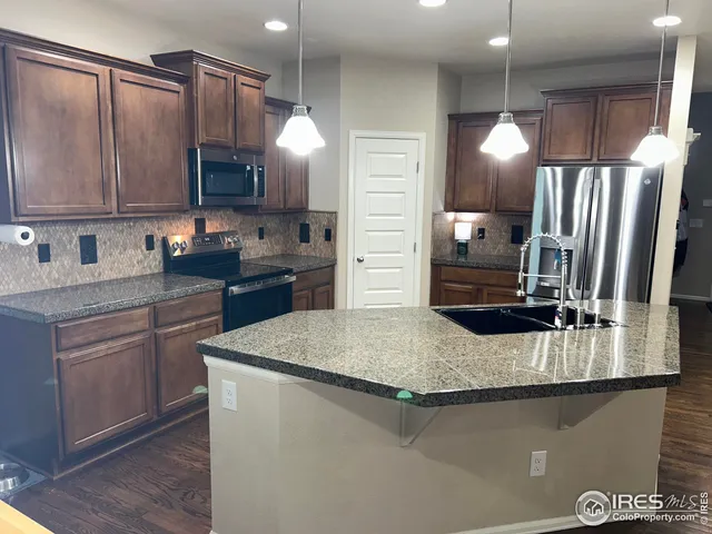 a kitchen with stainless steel appliances granite countertop a refrigerator and a sink