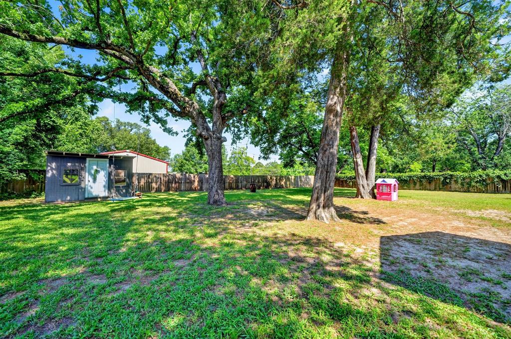 810 Edna Street Athens, TX 75751 - Photo 27 of 28 Expansive backyard featuring a large storage shed, mature trees, and a full perimeter fence