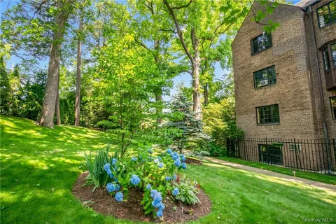 a view of a yard in front of brick house with a large tree