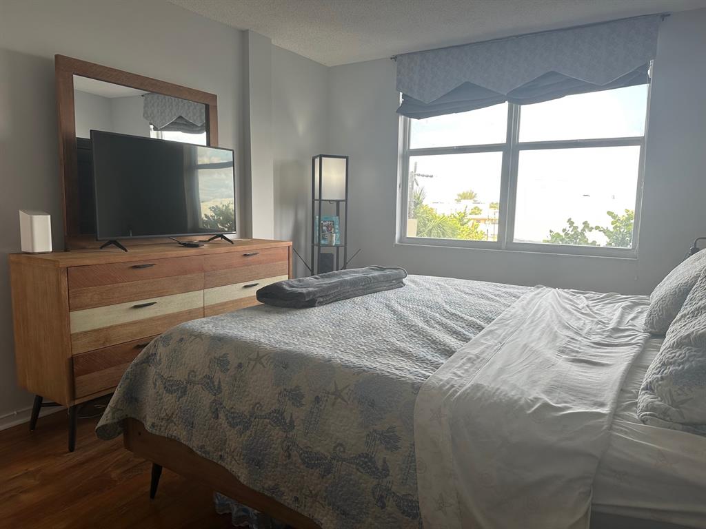 1009 North Ocean Boulevard, Unit 407 Pompano Beach, FL 33062 - Photo 16 of 35 a bedroom with a bed and a large mirror next to a window