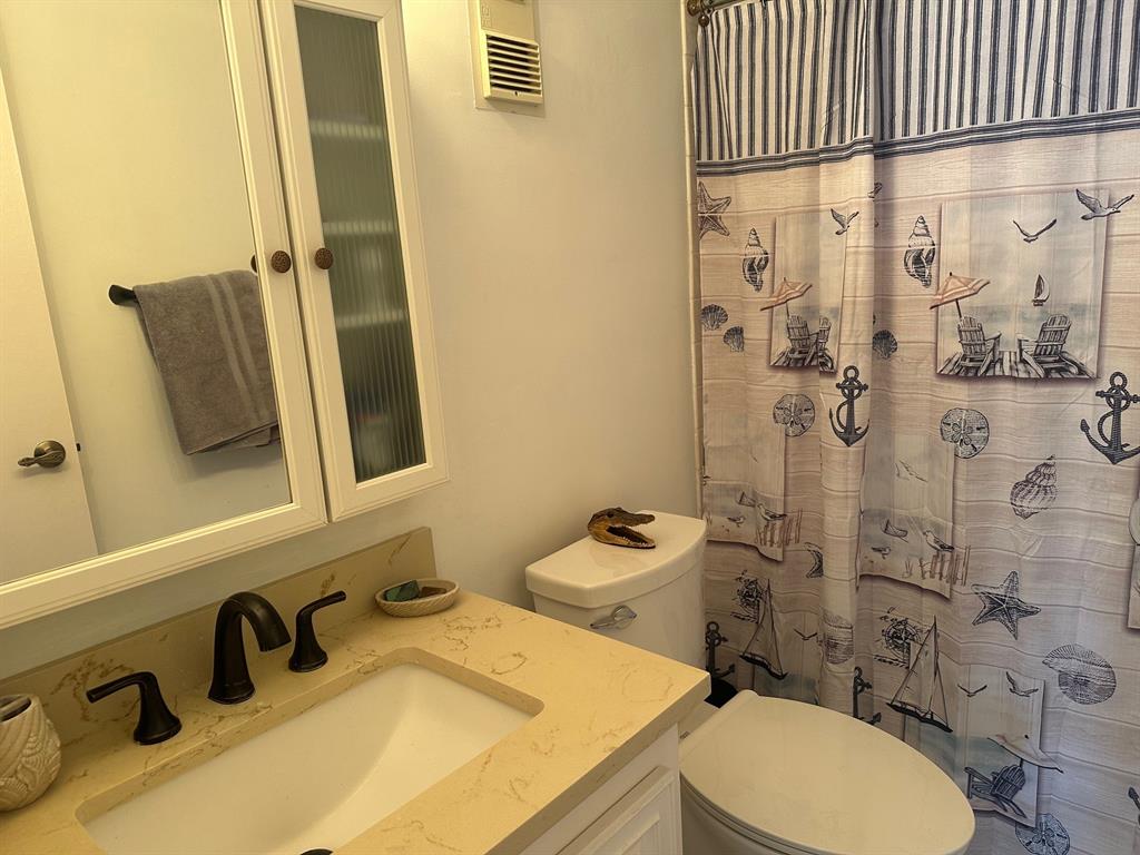 1009 North Ocean Boulevard, Unit 407 Pompano Beach, FL 33062 - Photo 19 of 35 a bathroom with a sink a toilet and shower curtain