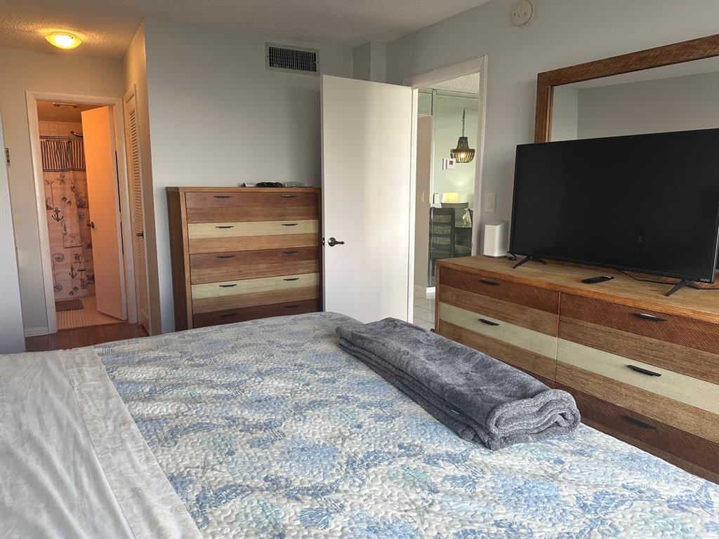 1009 North Ocean Boulevard, Unit 407 Pompano Beach, FL 33062 - Photo 20 of 35 a bedroom with a bed and flat screen tv