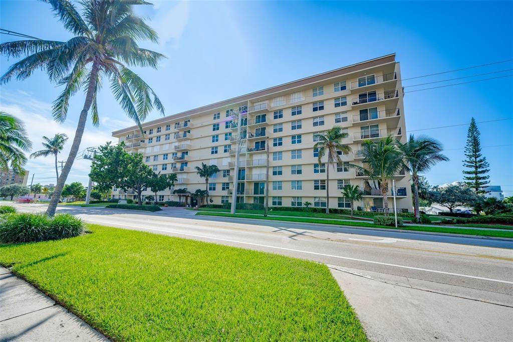 1009 North Ocean Boulevard, Unit 407 Pompano Beach, FL 33062 - Photo 3 of 35 a view of a tall building next to a yard with big trees