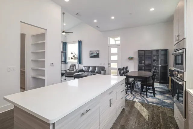 a large white kitchen with sink a refrigerator and chairs