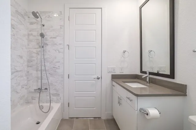 a bathroom with a granite countertop sink a mirror and shower