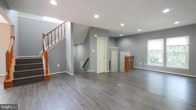 a view of an empty room with wooden floor and stairs