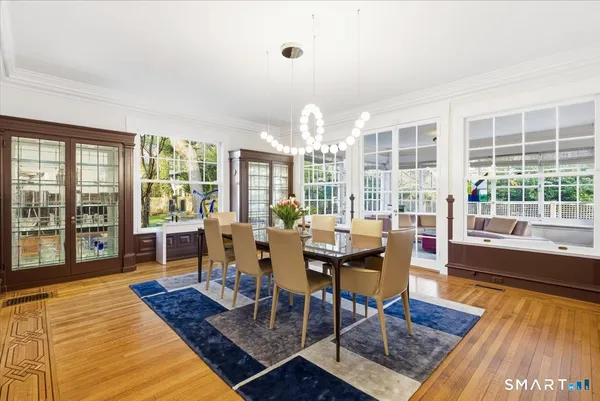 a dining room with wooden floor and large windows