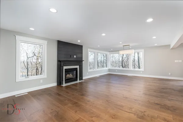 an empty room with windows fireplace and wooden floor