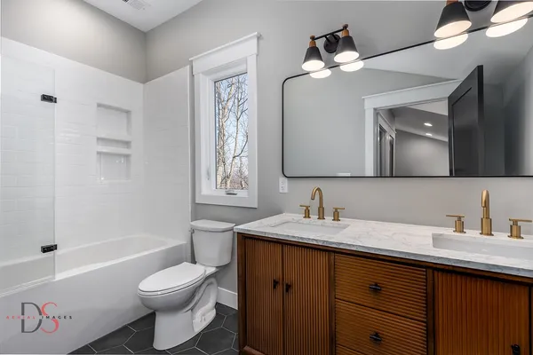 a bathroom with a toilet a sink a tub and a mirror