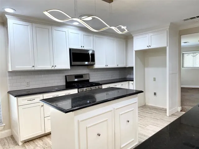 a kitchen with stainless steel appliances granite countertop a sink a stove a microwave and cabinets