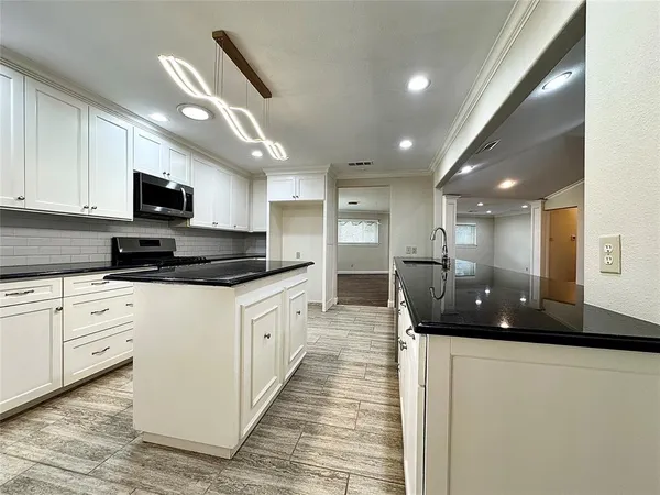 a large white kitchen with stainless steel appliances granite countertop a sink a stove and a refrigerator
