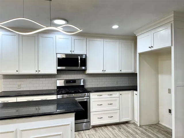 a kitchen with granite countertop a sink a stove and cabinets
