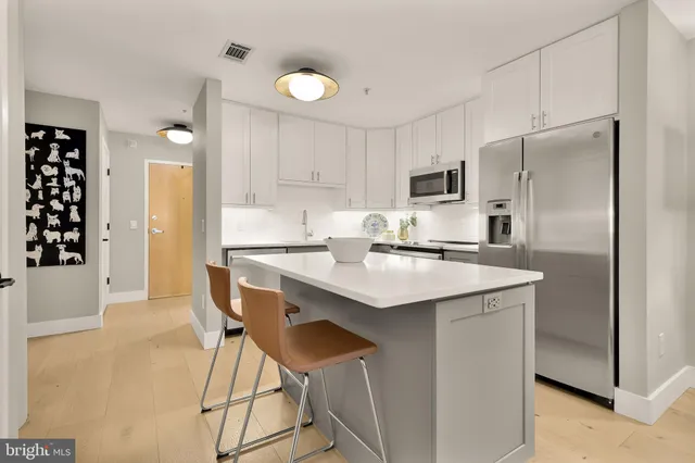 a kitchen with kitchen island a sink cabinets and stainless steel appliances