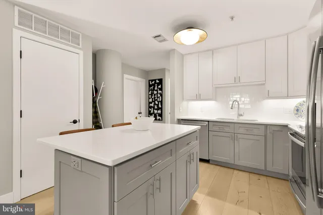 a kitchen with a sink dishwasher a stove and white cabinets with wooden floor