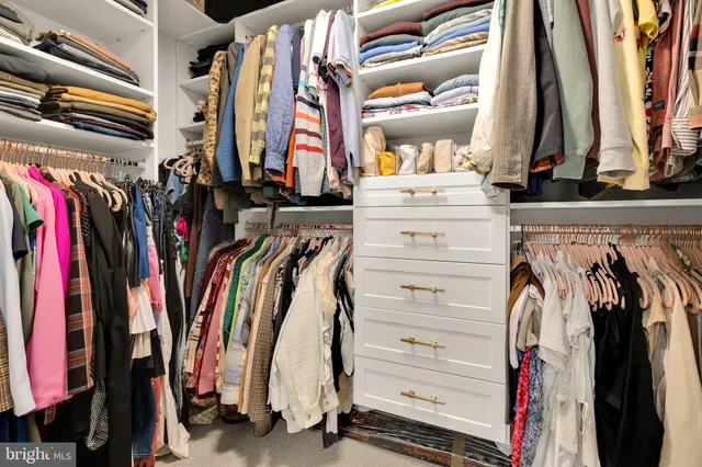 a view of walk in closet with clothes and shoes