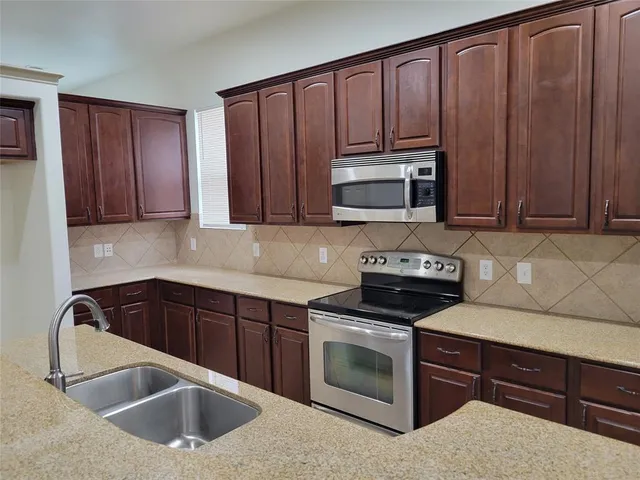 a kitchen with granite countertop a sink stove and microwave