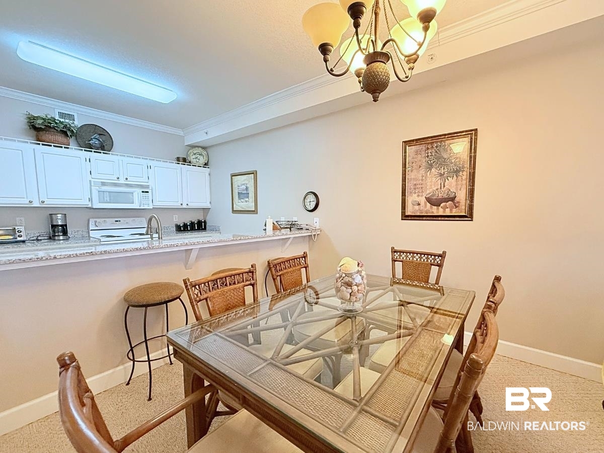 27284 Gulf Road, Unit 212 Orange Beach, AL 36561 - Photo 6 of 35 Dining room featuring ornamental molding, suspended lighting, and light carpet