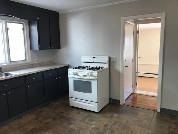 a kitchen with stainless steel appliances a stove and white cabinets