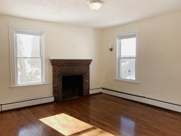 an empty room with wooden floor windows and fireplace