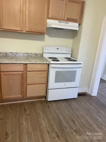 a kitchen with granite countertop white cabinets and a stove