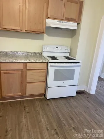 a kitchen with granite countertop white cabinets and a stove