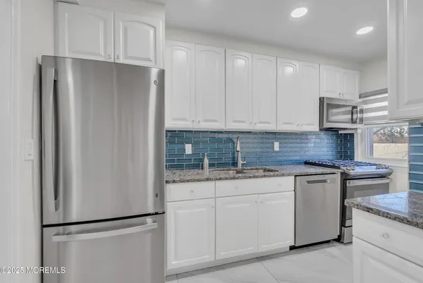 a kitchen with granite countertop a sink stove and cabinets