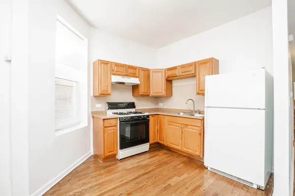 a view of a kitchen with wooden floor and a fireplace