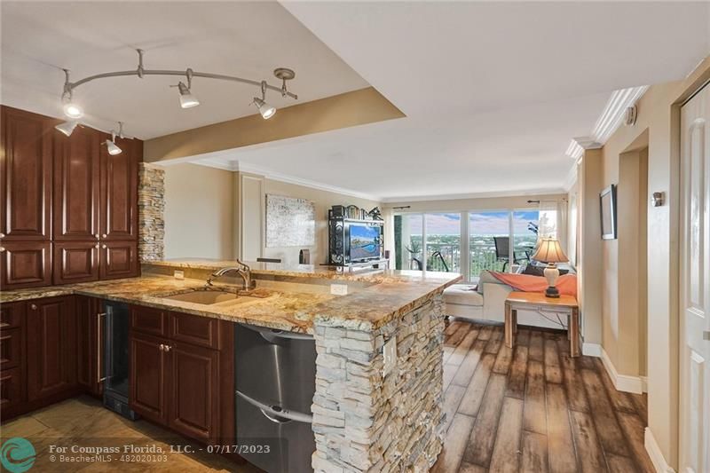 a dining hall with stainless steel appliances granite countertop a sink and wooden floor