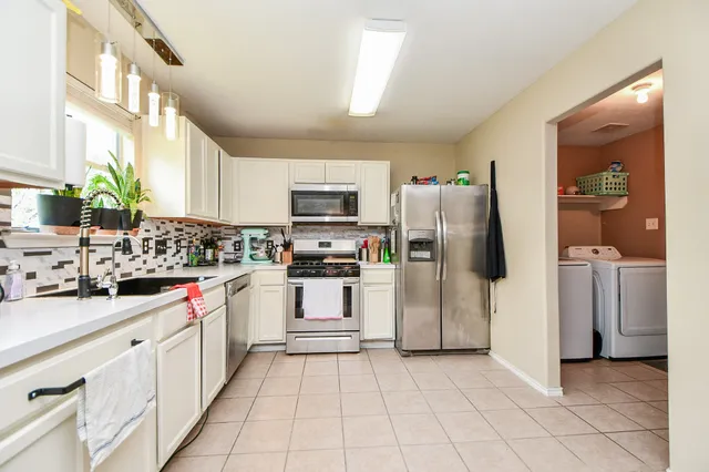 a kitchen with white cabinets and refrigerator