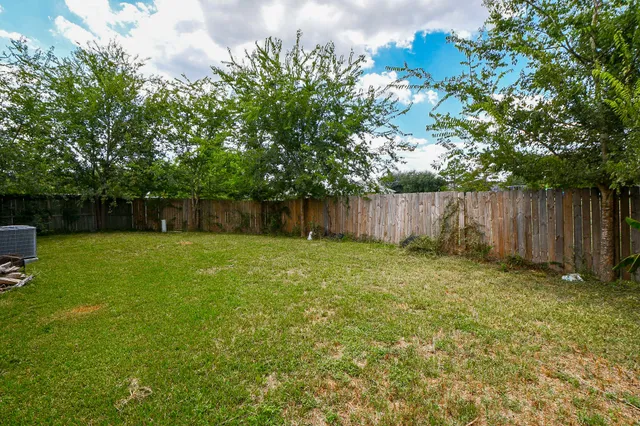 a view of a backyard with large trees and wooden fence