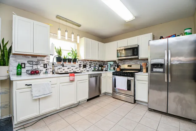 a kitchen with white cabinets stainless steel appliances and a window