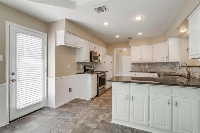 a kitchen with white cabinets and appliances