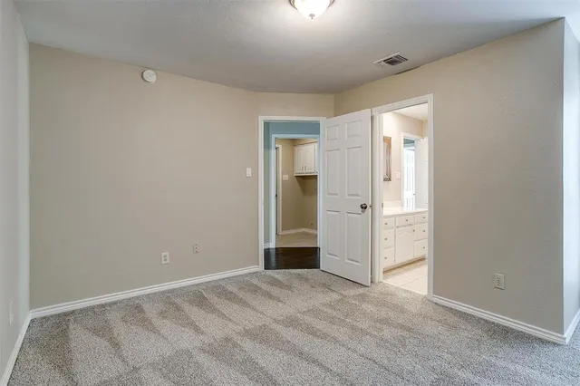 a view of an empty room with wooden floor and closet