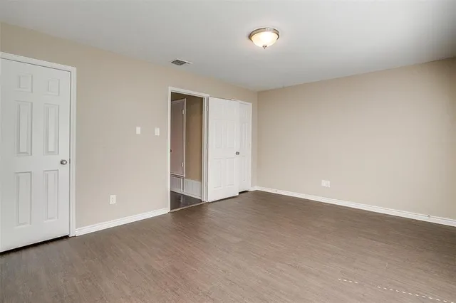 a view of an empty room with wooden floor and closet