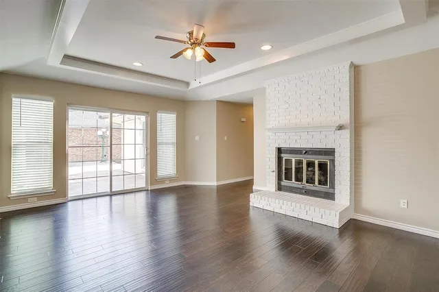 an empty room with wooden floor fireplace and windows