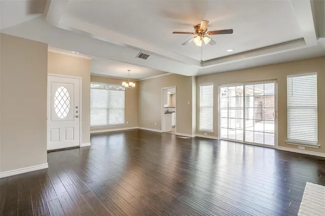 a view of an empty room with a window and wooden floor