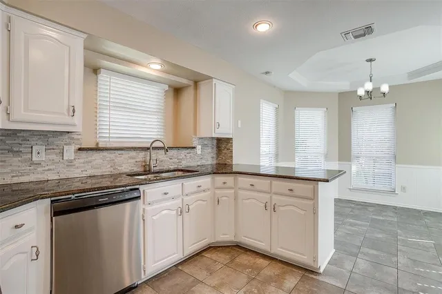a kitchen with granite countertop white cabinets white appliances with a sink and dishwasher
