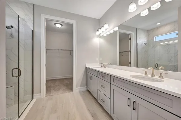 a spacious bathroom with a double vanity sink a large mirror and shower