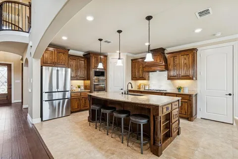 a kitchen with stainless steel appliances granite countertop a table chairs stove and refrigerator