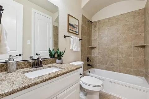 a bathroom with a granite countertop sink a toilet a mirror and bathtub